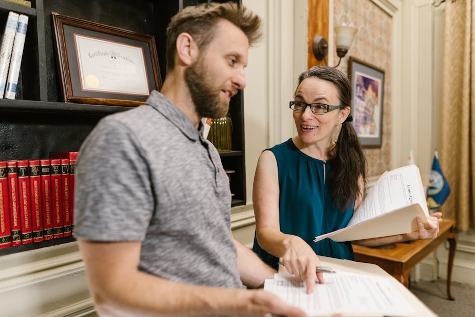 Two colleagues discussing legal documents in an office with certificates and books.